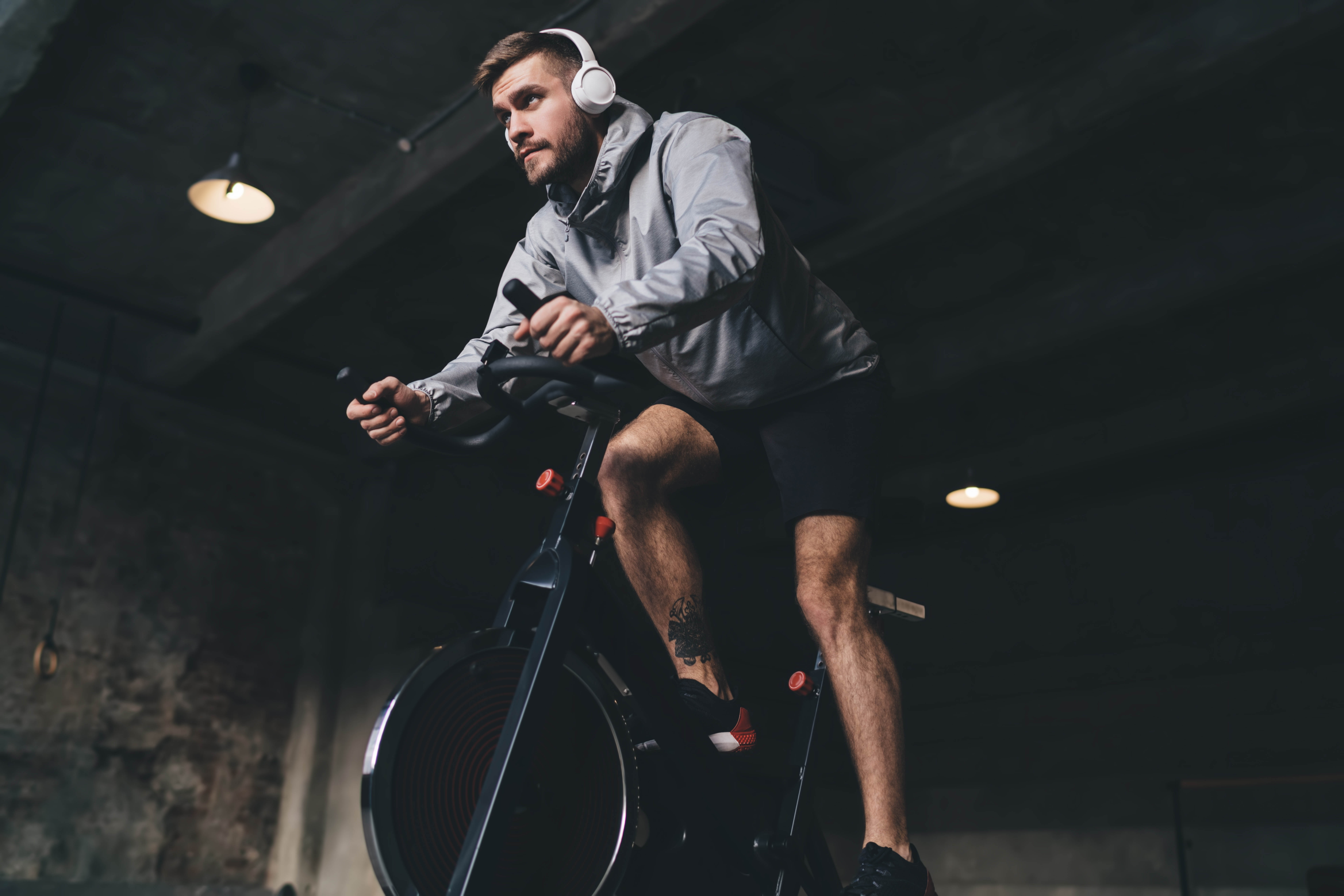 Man with headphones on, working out on a stationary bike in a gym